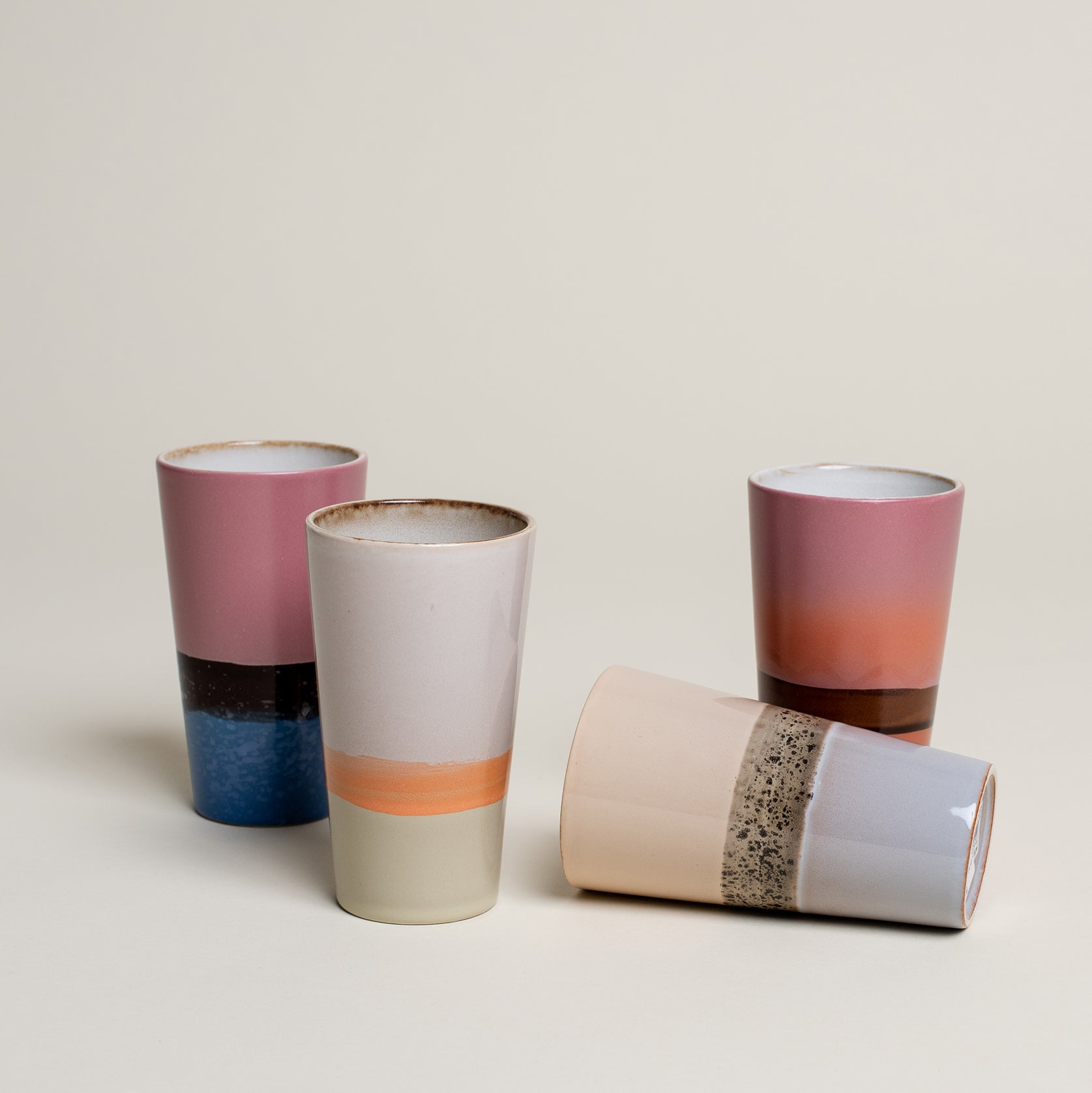 Vier Tassen im 70er retro Stil in unterschiedlichen Fraben von pink, blau, orange und Beige, grün und braun. Edit alt text