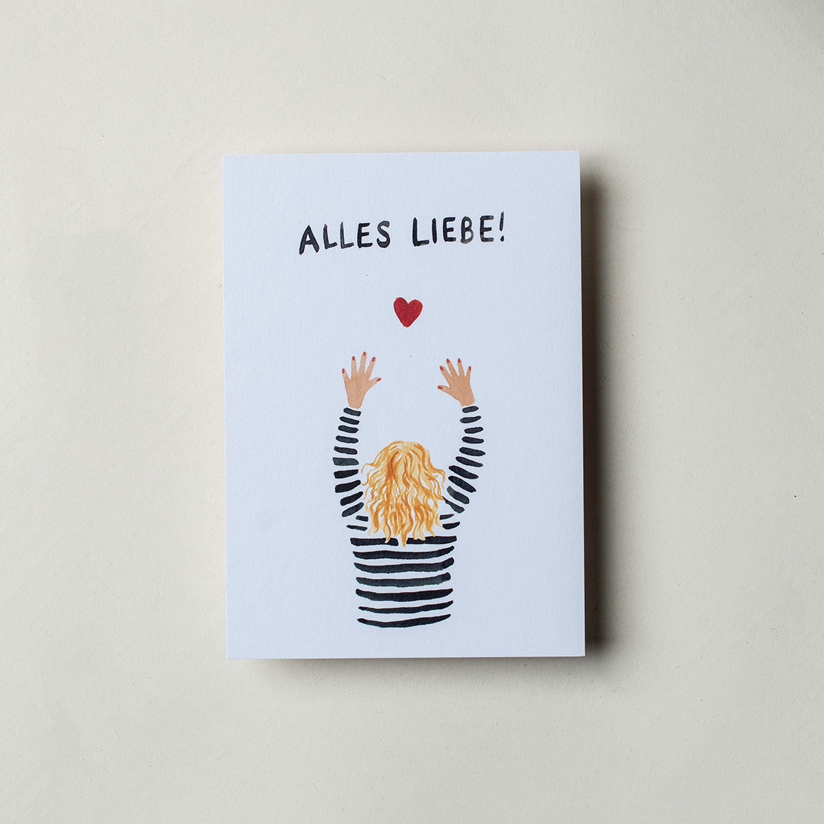 Postkarte mit der Aufschrift "Alles Liebe!" und einer bunten Zeichnung in der eine Person die Hände hoch hebt. Über den Händen und unter der Schrift ist ein rotes Herz gemalt.