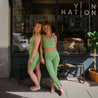 Mantis Compressive High Rise Leggings von Girlfriend Collective. Zwei Personen tragen eine Sport set in fröhlichem grün. Die Leggins hat einen hohen Bund und ist nachhaltig produziert. 