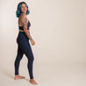 Midnight Compressive High Rise Leggings von Girlfriend Collective. Eine Person trägt eine Sport set in der Farbe dunkel blau. Die Leggins hat einen hohen Bund und ist nachhaltig produziert.